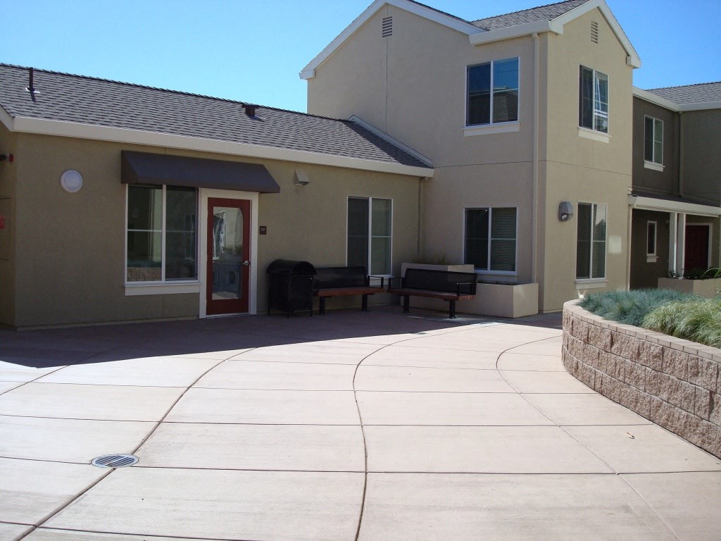 the front of a building with a concrete walkway and a bench