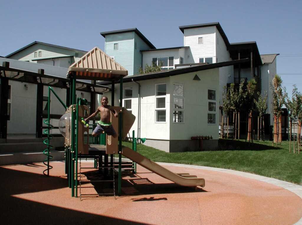a man playing on a playground     in front of a house