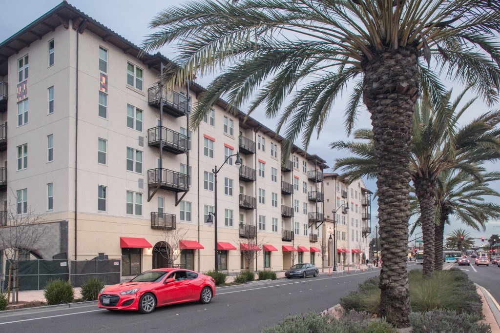 a red car parked in front of an apartment building a red car parked in front of an apartment building