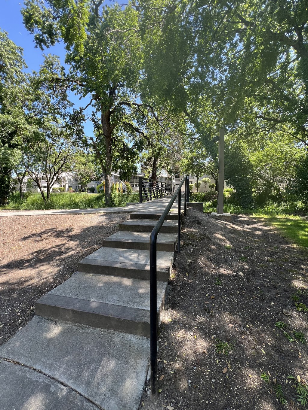 A set of stairs with a metal railing on the side going up a hill.