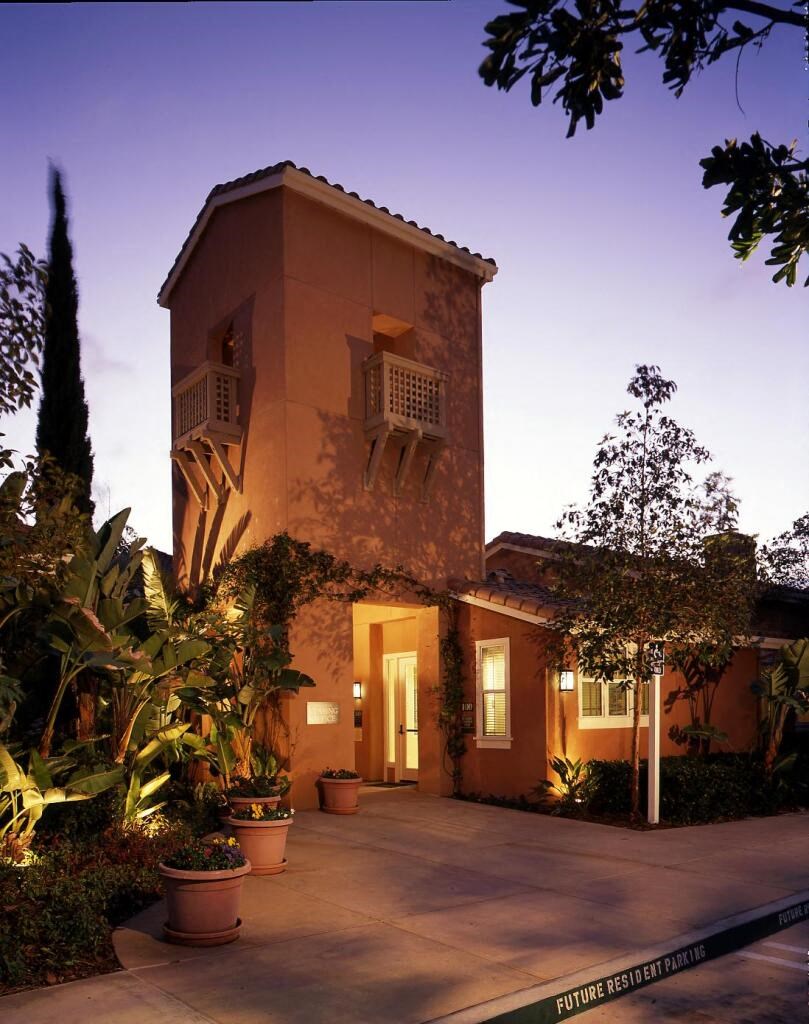 the house is lit up at night with plants and a courtyard