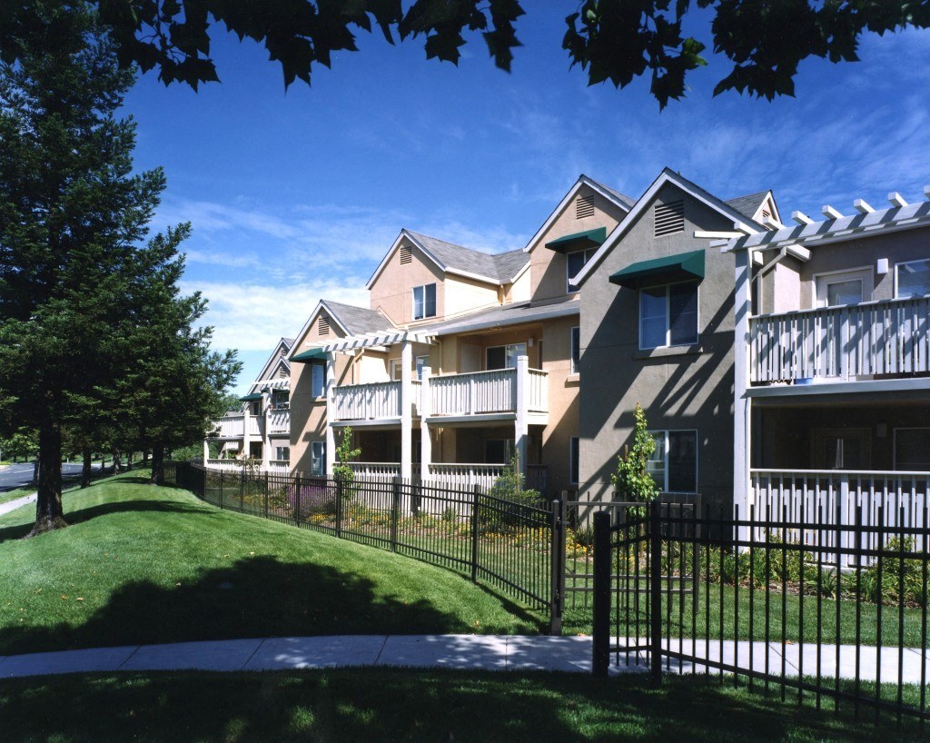 an apartment building with a yard and a wrought iron fence