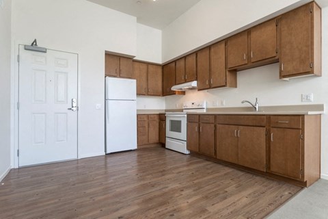 an empty kitchen with wooden cabinets and a white refrigerator