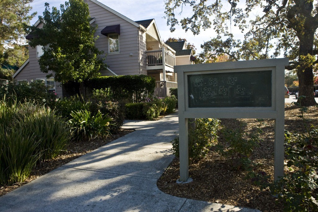 a sign in front of a house with a sidewalk