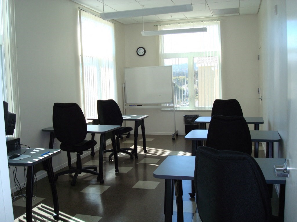 a classroom with tables and chairs and a whiteboard