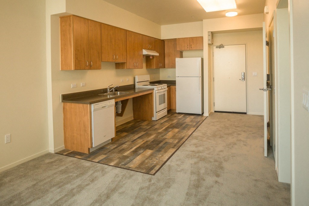 an empty kitchen with wood cabinets and a white refrigerator