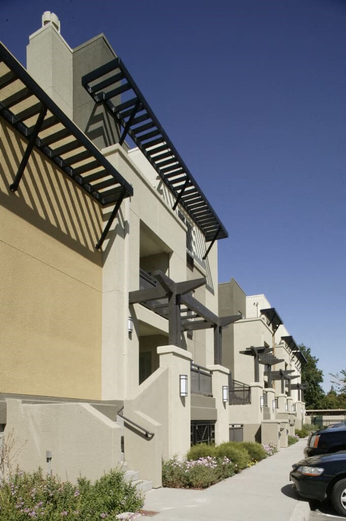 a row of apartment buildings with cars parked in front of them