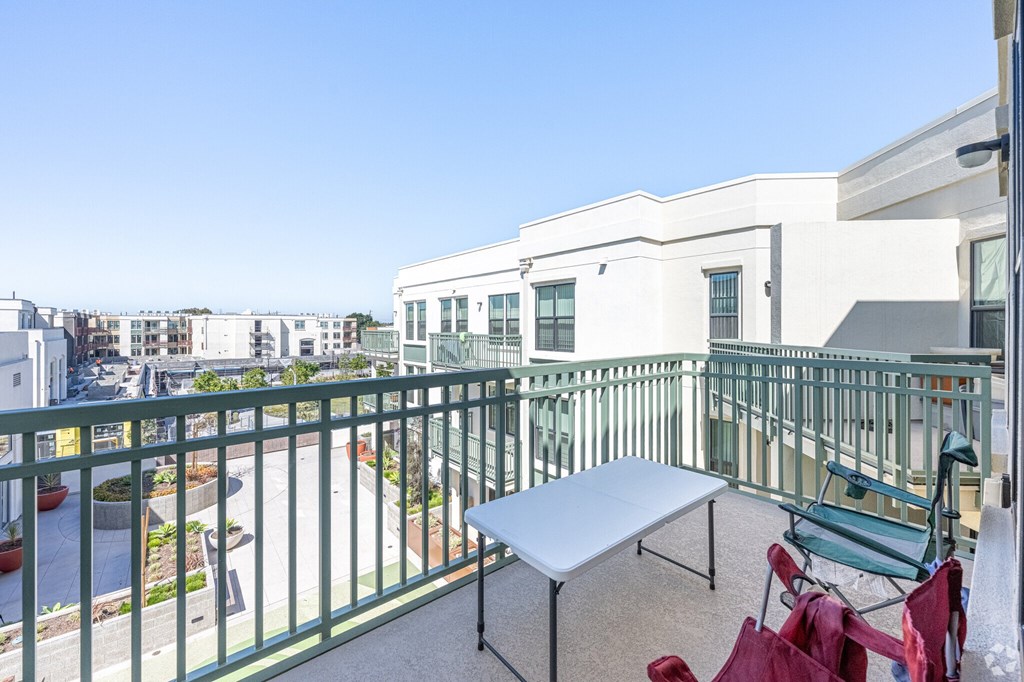 A balcony with a table and chairs overlooks a courtyard.