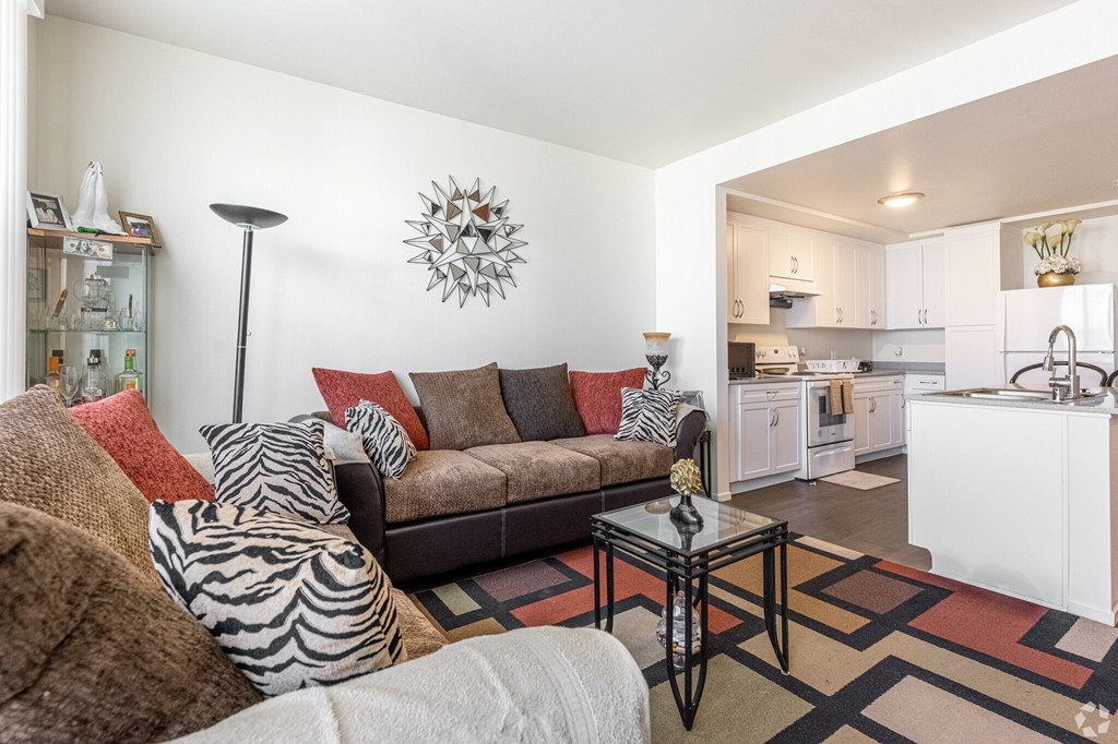 A living room with a brown couch and a glass table.