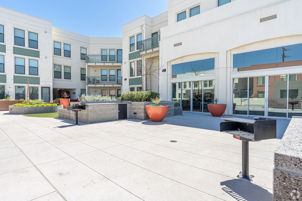 A courtyard with a mailbox in front of a building with orange planters.