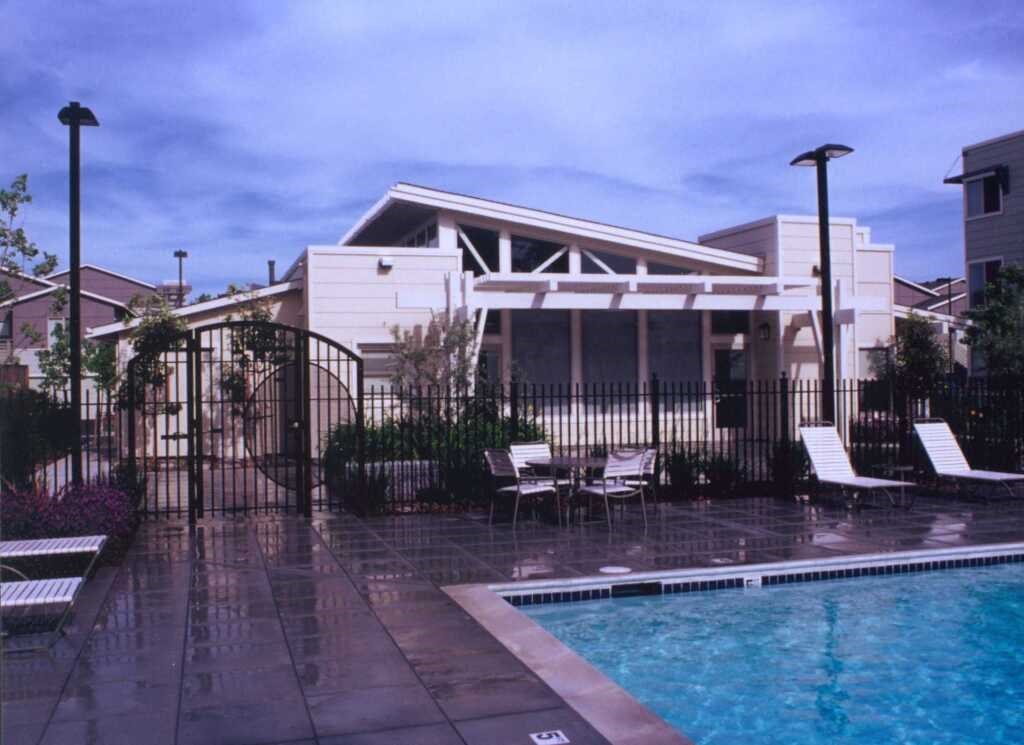 the pool and patio area of a pool house with chairs