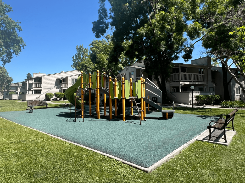 A playground with a green surface and a yellow structure.