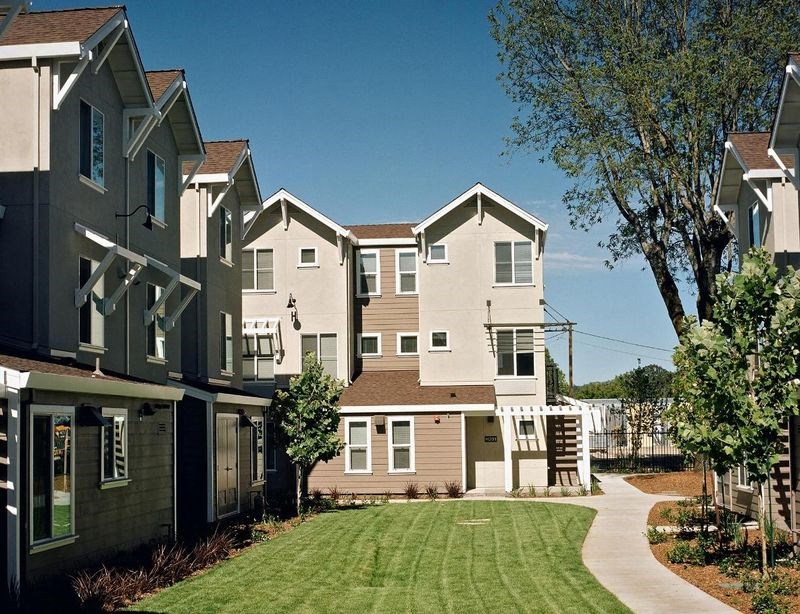 a row of houses with a green lawn and trees