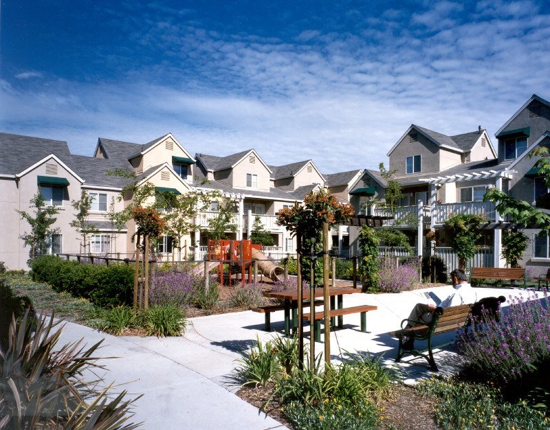 a man sitting on a bench in a courtyard in front of houses