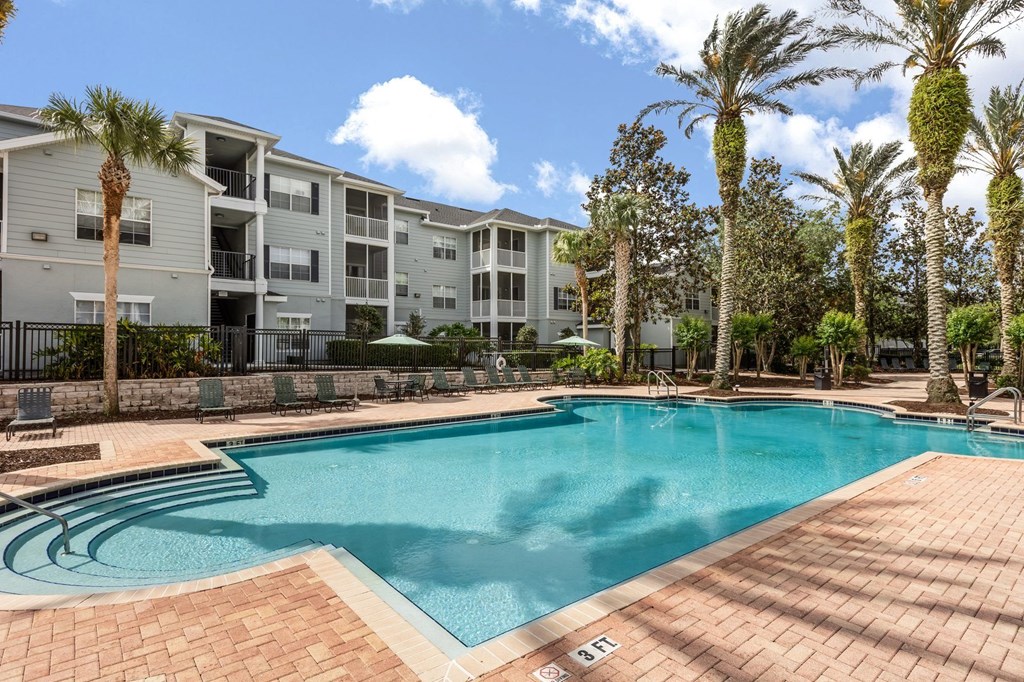 A swimming pool surrounded by palm trees and apartment buildings.