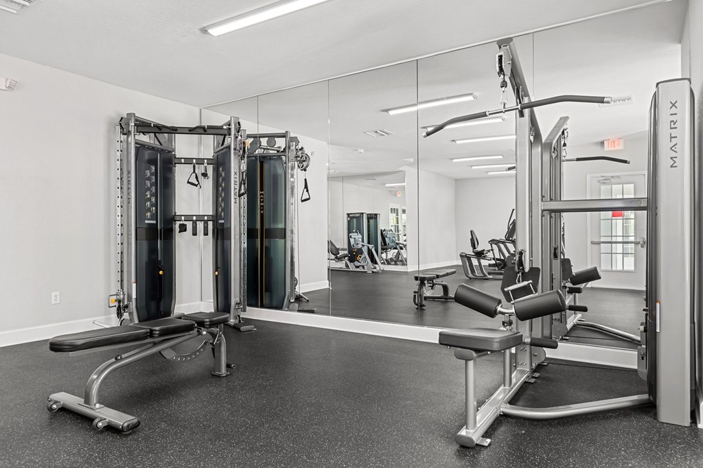 A gym with a mirror, a bench, and a weight machine.