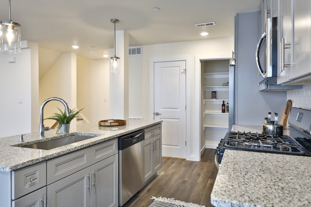 a kitchen with grey cabinets and island with pantry