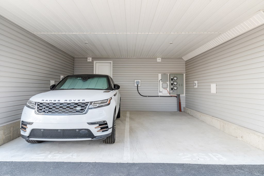 a white car parked in a garage in front of an electric car charger