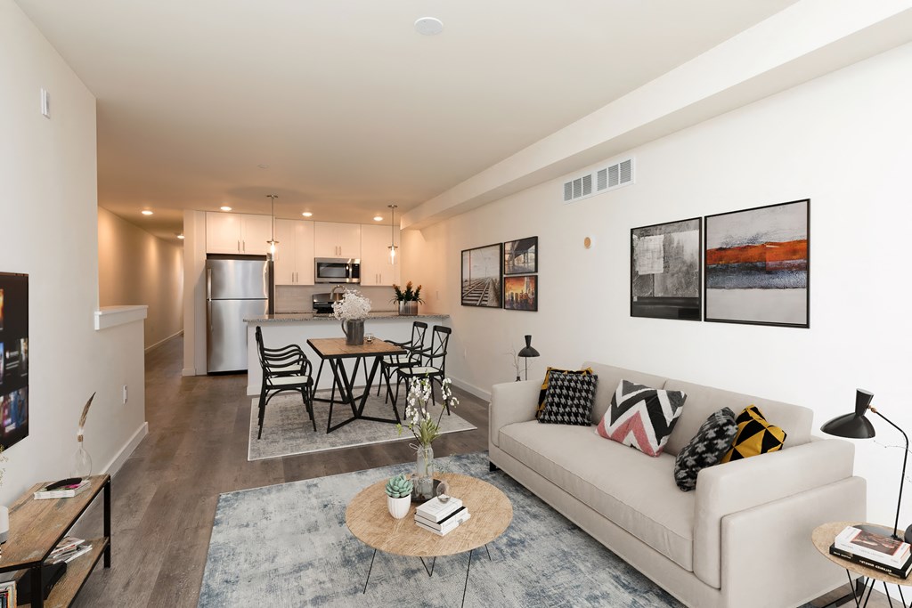a living room with a couch and a table in front of a kitchen