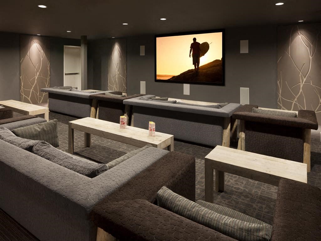 a room with couches and tables and a screen on the wall