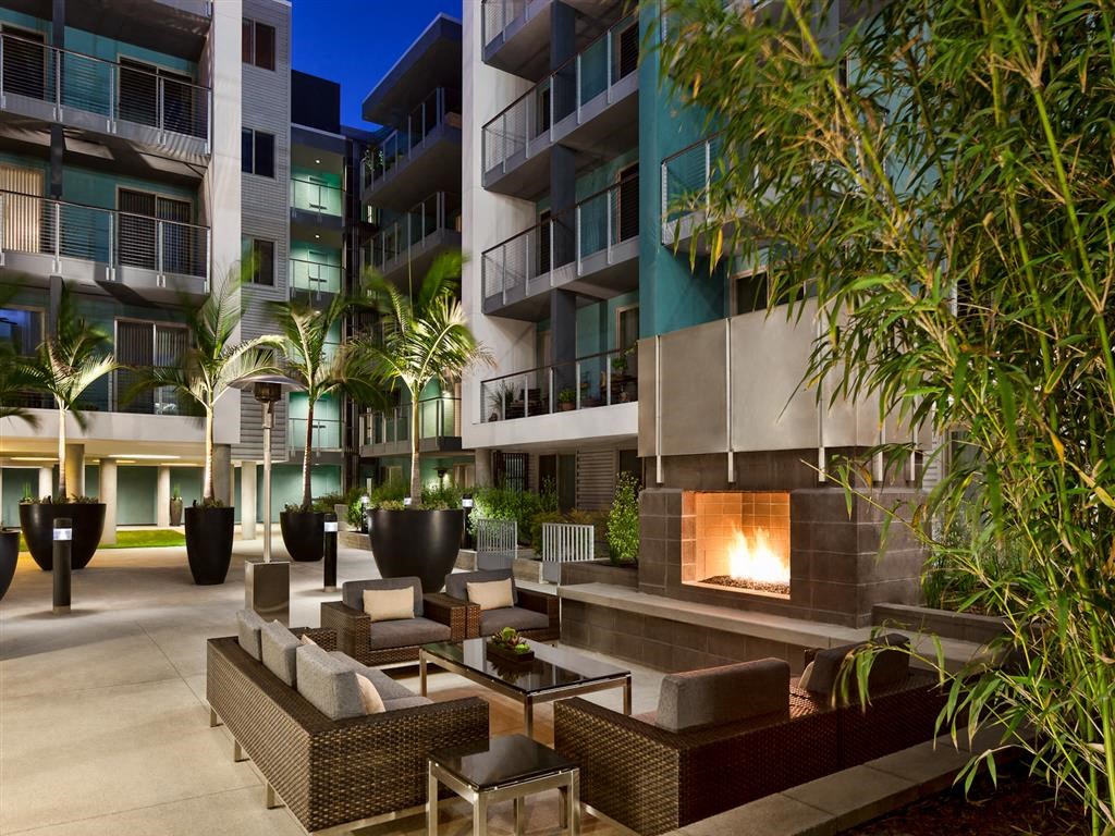an outdoor area with a fireplace and seating in front of an apartment building