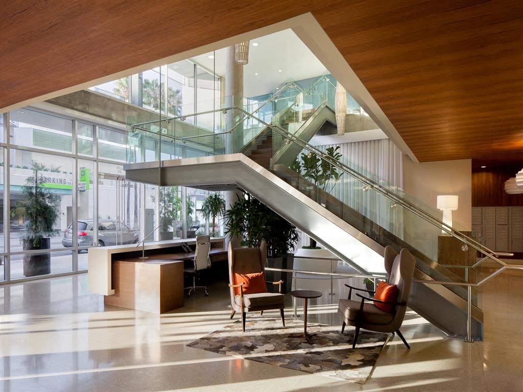 the lobby of a building with an escalator and a table and chairs