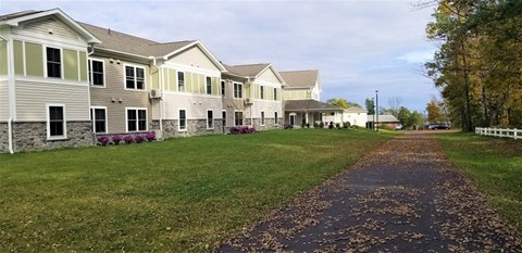 A long path with leaves on it leading to a building.