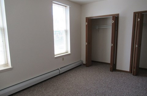 A room with a carpeted floor and a large mirror.