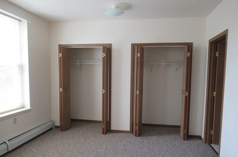Two open closet doors in a white room.