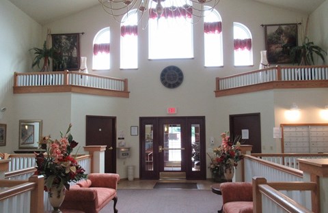 A church interior with a red bench and a flower arrangement on a table.