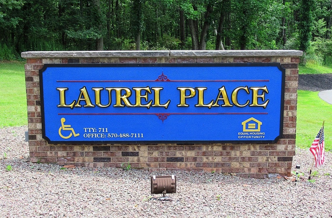 A sign that says Laurel Place with a phone number and a house icon.