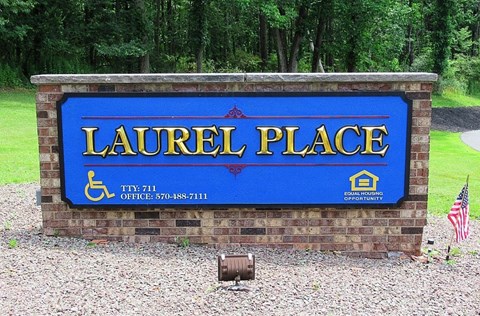 A sign that says Laurel Place with a phone number and a house icon.