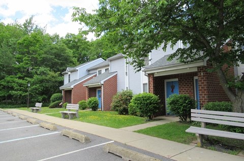 A parking lot in front of a building with a bench on the sidewalk.
