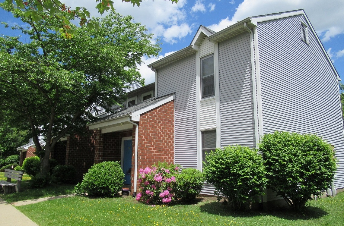 A house with a grey siding and a brick chimney.