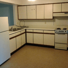 A white fridge sits in a kitchen with white cabinets.