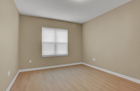 A room with a window and wooden flooring.
