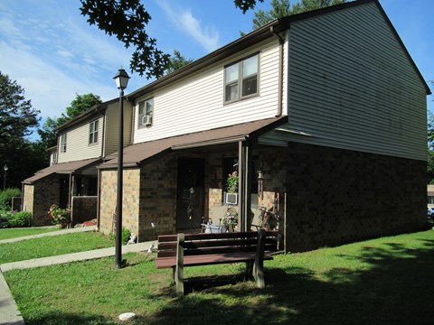 A house with a brown roof and a bench in front of it.