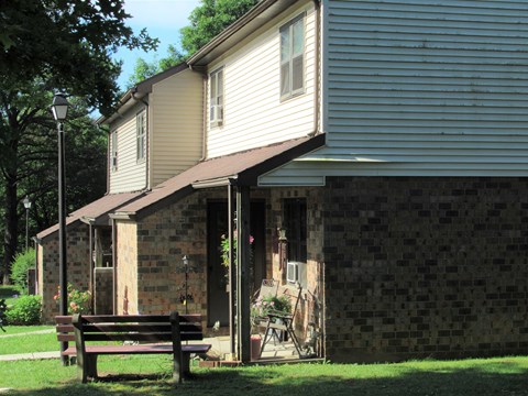 A house with a brown bench in front of it.