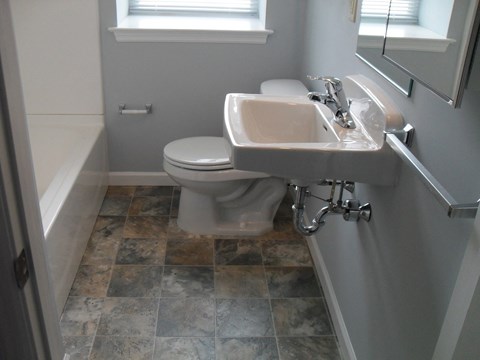 A white toilet is in a bathroom with a sink and a window.