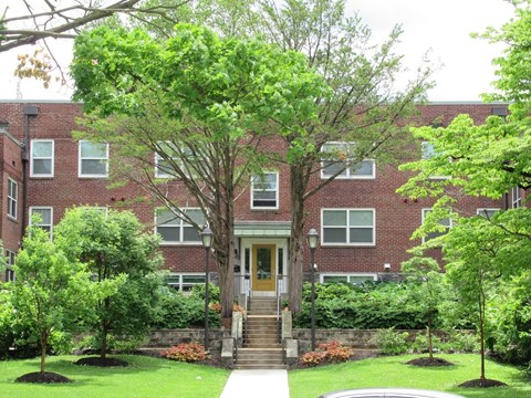 A red brick building with a wooden door and steps leading up to it.