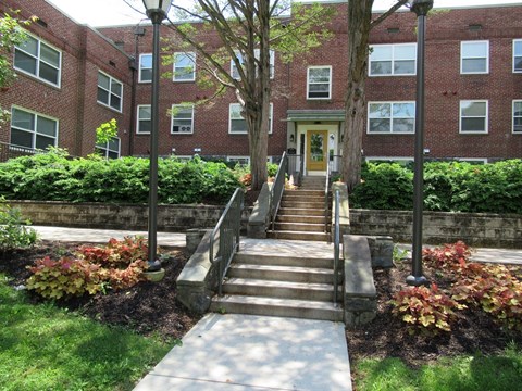 A red brick building with a yellow door and steps leading up to it.