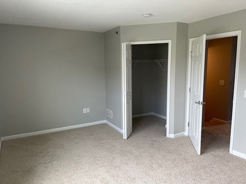 A room with a carpeted floor and two open doors.