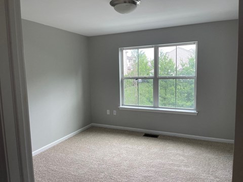 A room with a window and carpeted floor.