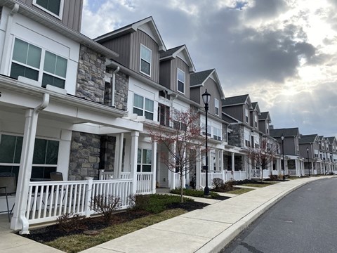 A row of houses with white fences and green trees.