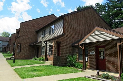 A brick building with a red door and a sign on the front.