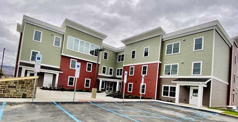 A parking lot in front of a building with a red and green facade.