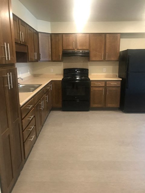 A kitchen with wooden cabinets and black appliances.
