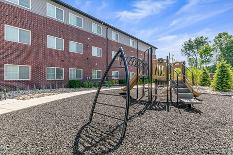A playground with a slide and a building in the background.