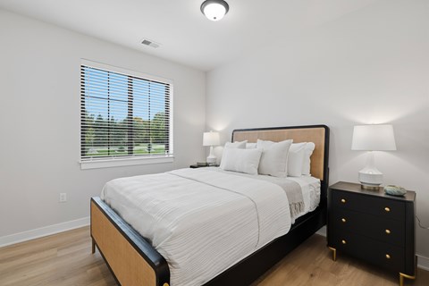 A bedroom with a large bed and a nightstand with a lamp.