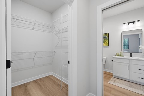 A white walk-in closet with shelves and a mirror.
